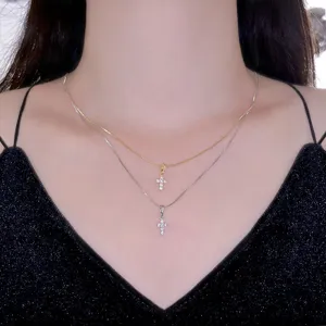 Detail of layered gold and silver cross pendants on a delicate box chain necklace.