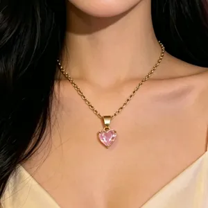 Close-up shot of a gold-tone chain necklace featuring a sparkling pink heart crystal pendant.