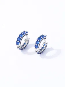 Primo piano di eleganti orecchini a cerchio color argento con zirconi blu scintillanti