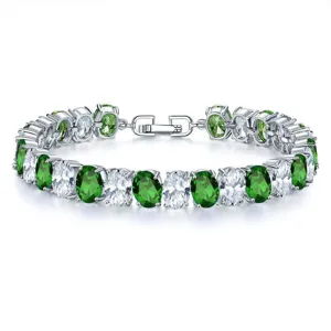 Close-up detail of luxurious women's bracelet with oval green and clear zircon stones.