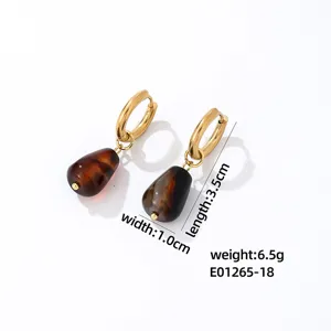 Detail view of stylish gold hoop earrings featuring elegant brown teardrop gemstone pendants.