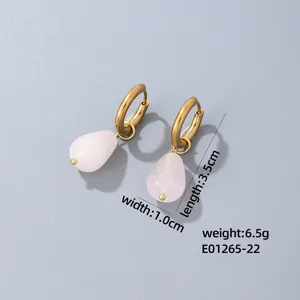 Detail shot of elegant gold-plated drop earrings with pink gemstone pendants, chic and stylish.