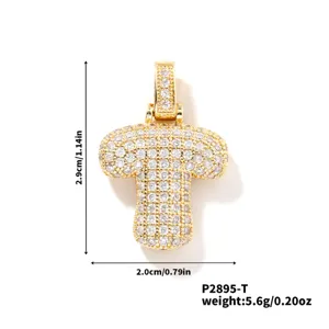 Vue détaillée du pendentif lettre T glacé présentant des pierres scintillantes et finition or.