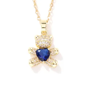 Close-up of a sparkling gold bear pendant with a deep blue heart-shaped crystal.