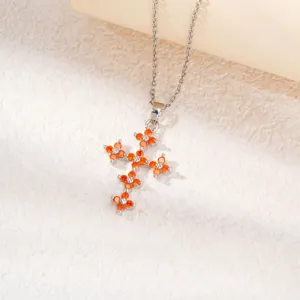 Détail d'un collier pendentif croix en argent serti de zircones cubiques orange