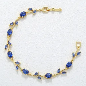 Elegante gouden wijnstok armband met blauwe kristallen op een witte achtergrond