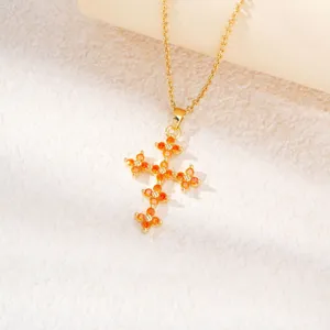 Détail du collier pendentif croix trèfle orné de zircons orange éclatants et dorés.