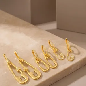 Macro view of various 16K gold-plated safety pin earrings with sparkling zircon inlay.
