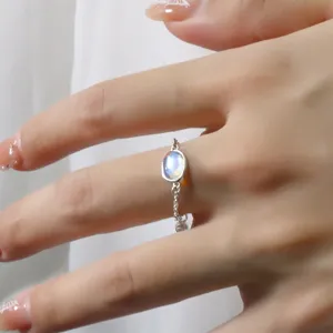 Close-up of adjustable silver chain ring featuring an oval moonstone on finger