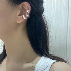 Close-up of minimalist silver ear cuff set with star and square stone on ear.