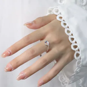 Close-up of a silver adjustable chain ring with an oval iridescent moonstone on a hand