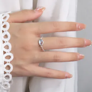 Close-up detail of elegant silver chain ring featuring an iridescent oval moonstone