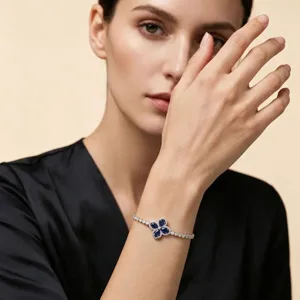 Detail view of a silver-toned clover bracelet with blue and clear zircon stones.