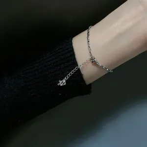 Close-up detail of silver chain bracelet featuring H letter charm and cross pendant