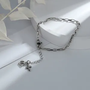 Detail view of silver-toned bracelet with cross and letter H square tag charms