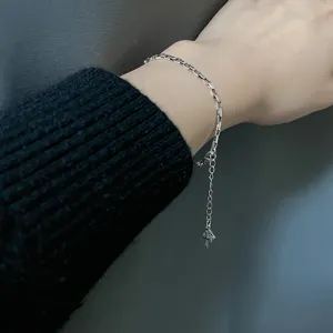 Detailed close-up of a minimalist silver square link chain bracelet with a cross pendant