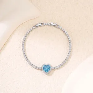 Detail eines luxuriösen Kupferarmbands mit herzförmigem blauem Zirkon und Vollbesatz.