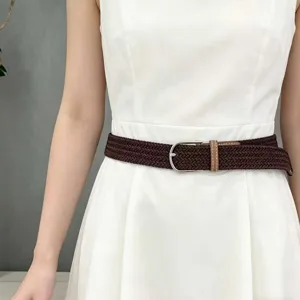 Detailweergave van een bruine elastische gevlochten riem met zilveren gesp op witte jurk