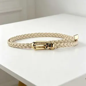 Close-up of a stylish braided thin belt with a shiny gold metal buckle for dresses.