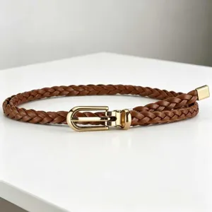 Detailed view of brown braided leather belt with gold metal buckle, stylish accessory.