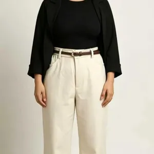 Close up of thin brown leather belt worn with high waist trousers and black blazer detail.