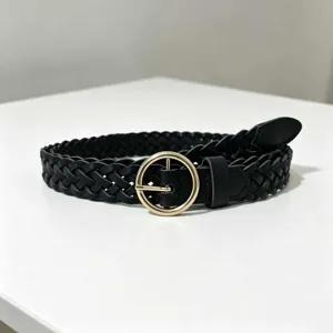 Black braided belt with round gold buckle for women, stylish detailed view of woven leather texture.
