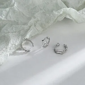 Macro detail view of three silver minimalist ear cuffs featuring star and square stone accents.