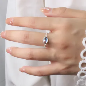 Close-up view of a minimalist silver chain ring with an iridescent oval moonstone