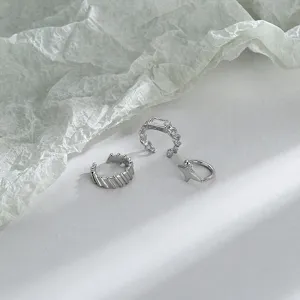 Detail view of three silver non-piercing ear cuffs featuring star and zircon chain designs