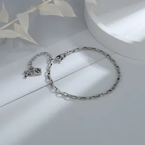 Detailed macro view of vintage silver chain bracelet with cross and H letter charms