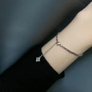 Detailed macro view of a minimalist silver chain bracelet featuring an H-letter charm