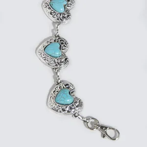 Detail shot of a vintage metal waist chain featuring carved hearts with turquoise stones.