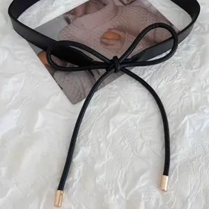 Detailed shot of a stylish black leather bow belt, perfect for dresses and coats.