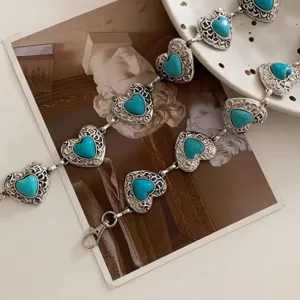 Detailed view of vintage heart-shaped turquoise waist chain with ornate metal engraving