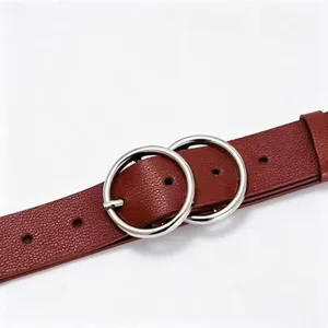Detail shot of a womens dark red PU leather belt featuring shiny silver double round metal rings.