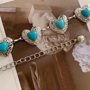 Macro detail of retro heart-shaped turquoise waist chain with intricate silver scrollwork