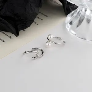 Detalle macro de clips para orejas con nudo de perlas plateadas y diseño vintage
