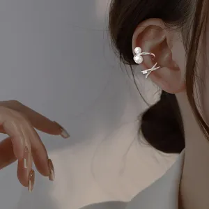 Vista detallada de un elegante ear cuff plateado con perlas y diseño de nudo fino