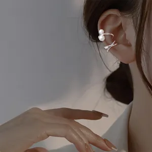 Primer plano de elegantes pendientes de clip plateados con nudo y perlas en la oreja