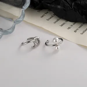 Primer plano de un conjunto de pendientes de clip plateados con nudo y perlas blancas