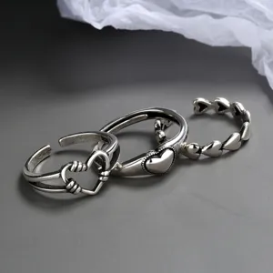 Close-up of vintage Thai silver open rings with intricate heart designs and oxidized finish.