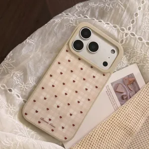Détail macro d'une coque de téléphone beige à carreaux avec cœurs rouges pour iPhone