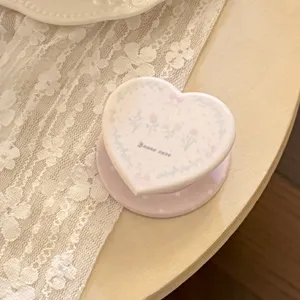 Close-up of a vintage heart-shaped phone grip featuring elegant French floral patterns and text