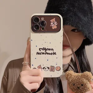 Detail of cute cream iPhone case featuring printed text and a plush bear lanyard