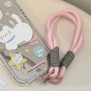Détail d'une dragonne de téléphone tressée rose attachée à une coque motif chat mignon