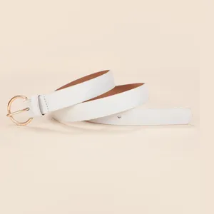 Primo piano dettaglio cintura in pelle bianca con fibbia rotonda dorata lucida e stile minimalista.