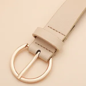 Cintura minimalista da donna in pelle beige con fibbia metallica rotonda, dettaglio elegante.