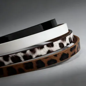 Detailed shot of four stacked thin women's belts in black, white, and leopard print.