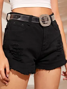 Detalle de un cinturón de PVC transparente con hebilla de pedrería sobre shorts vaqueros negros