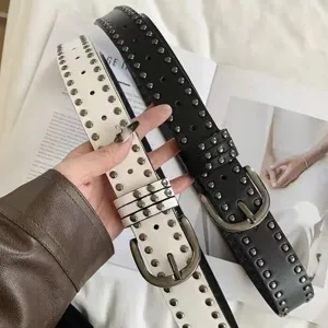 Detail view of black and white vintage studded belts with metallic buckles for women.